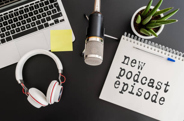 directly above shot of podcast recording equipment on desk with words new podcast episode written on note pad